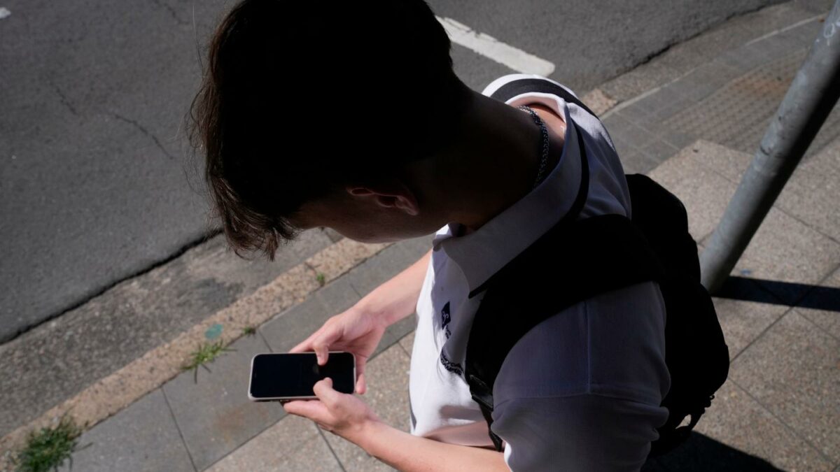 Photo of a kid staring at their phone with a shadow overhead