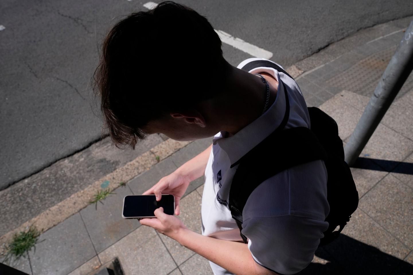 Photo of a kid staring at their phone with a shadow overhead