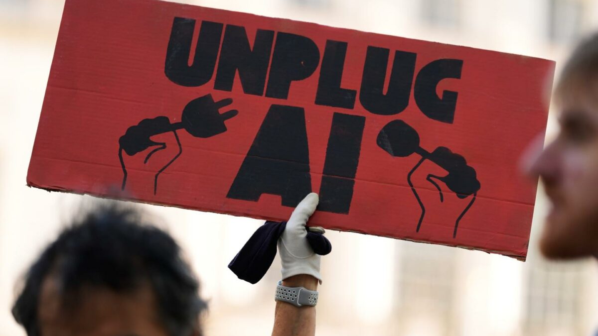A small group of people supporting restrictions on artificial intelligence hold up signs in front of City Hall before a New York City Council hearing on artificial intelligence safety in New York.