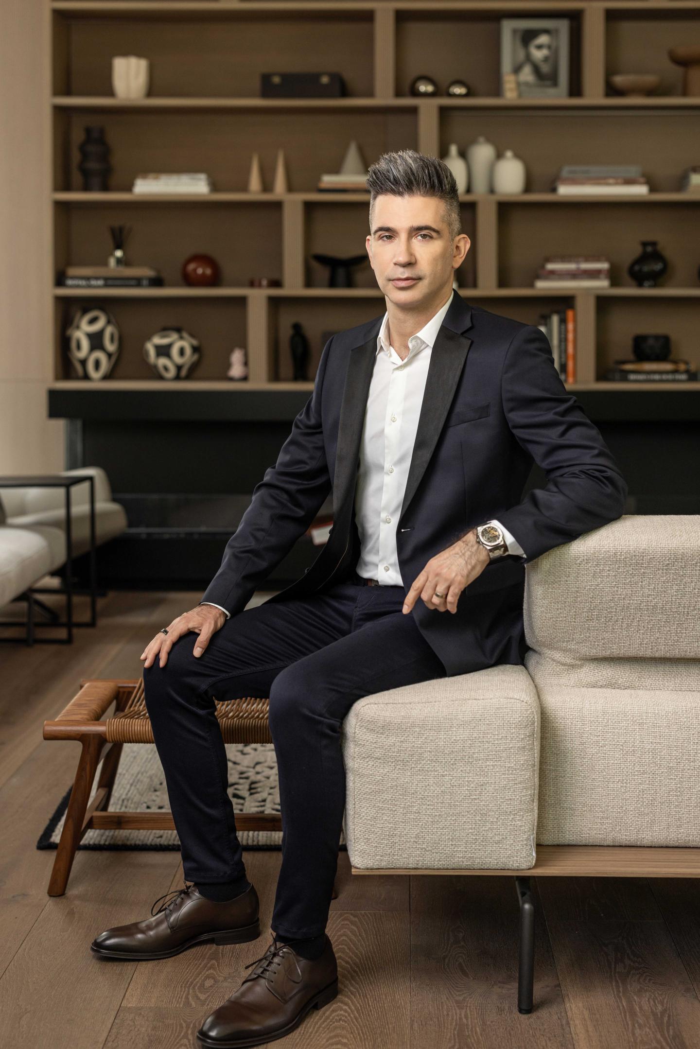 avishag-shaar-yashuv Yevgeny Dibrov wears a suit and sits on a couch