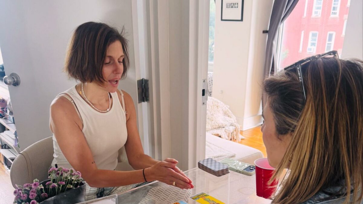 Tara’s Tarot, a practitioner on Divina, gives a tarot reading to an attendee at a Divina event.
