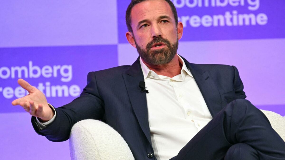 Ben Affleck wearing a suit jacket, behind a purple background
