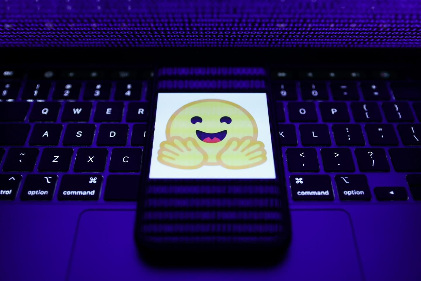 gettyimages-1246536583-e1788511225344-1 The Hugging Face logo on a smartphone resting on a laptop keyboard.