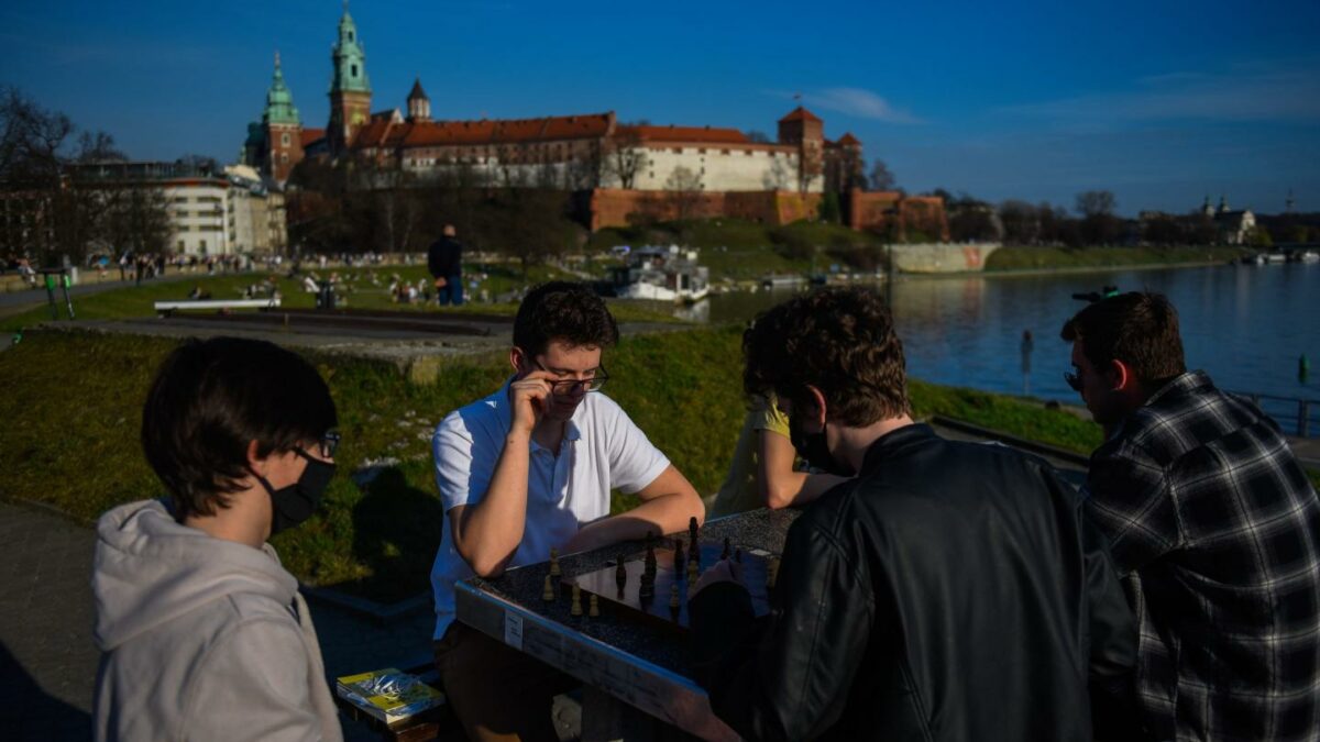 Photo of teenagers playing chess outside