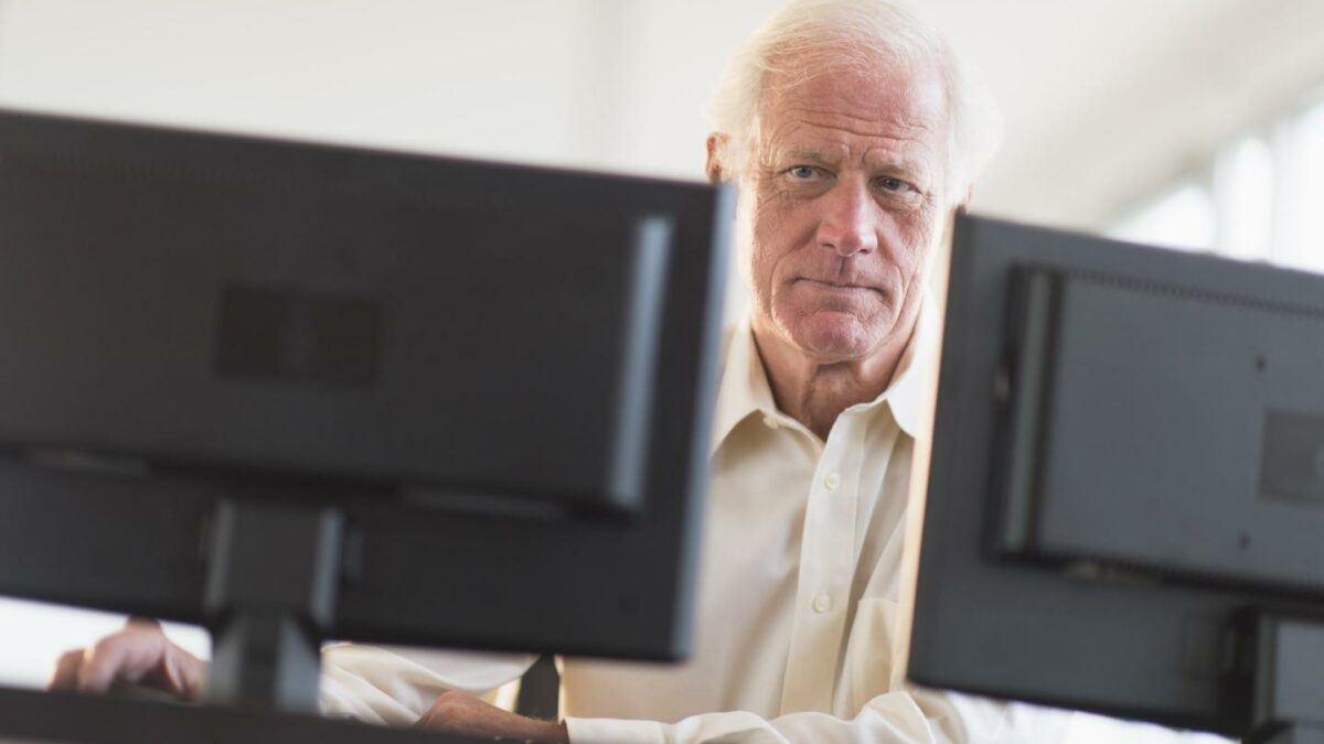 Photo of an older man working at two monitors