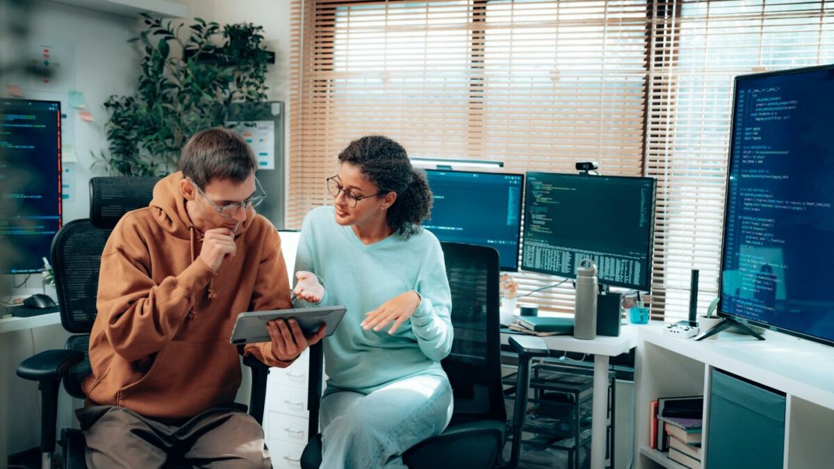 Latina software developer reviewing code with colleague in office