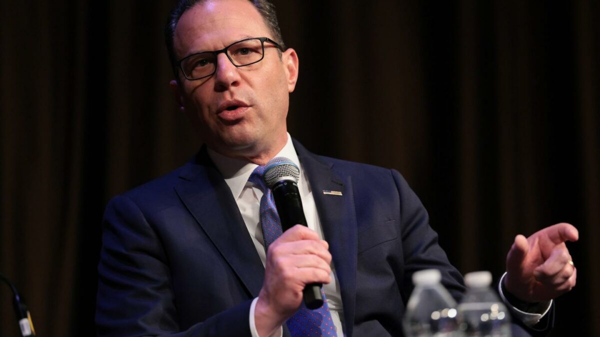 Josh Shapiro, wearing a suit, speaks into a microphone.
