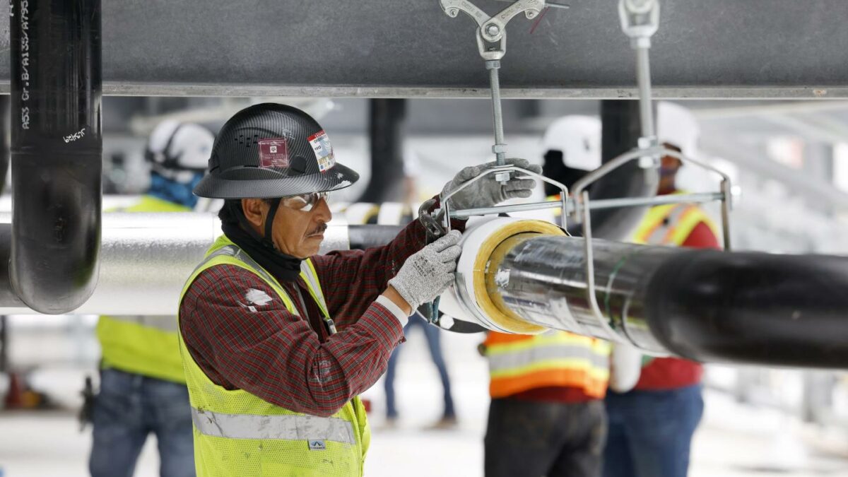 Construction workers build out the rooftop chillers and water lines feeding them atop Dallas TX4, which is under construction at the NTT Data center campus in Garland, Texas