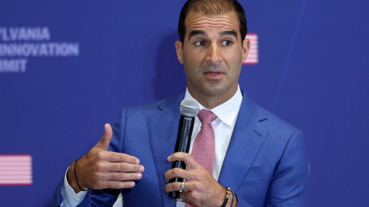 Dino Mavrookas wearing a blue suit and holding a microphone