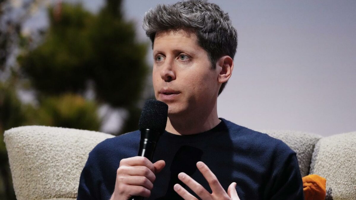 Sam Altman, sitting and holding a microphone to his mouth