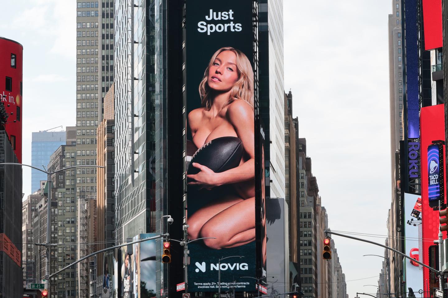 Billboard image of Sydney Sweeney Novig ad where she poses naked with a football covering her chest.