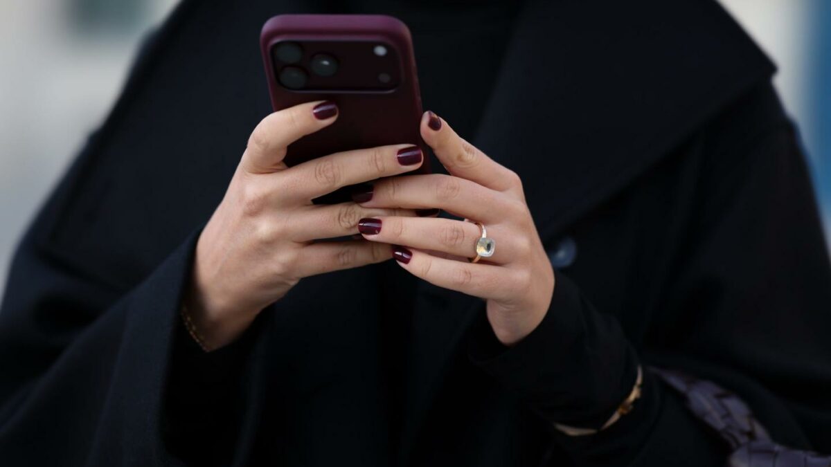 A woman holds a burgundy Apple iPhone 18 Pro during Paris Fashion Week on October 2, 2026. (Photo: Moritz Scholz/Getty Images)