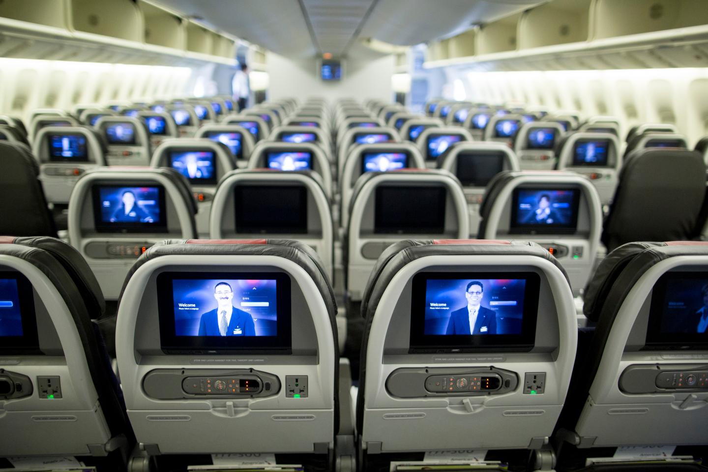 Screens are illuminated in the economy-class cabin on board an American Airlines Group Inc. Boeing Co. 777-300ER aircraft at Hong Kong International Airport in Hong Kong, China, on Friday, June 13, 2014.