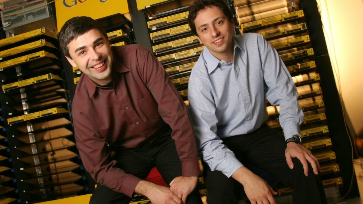 Larry Page and Sergey Brin smile in front of old Google servers.