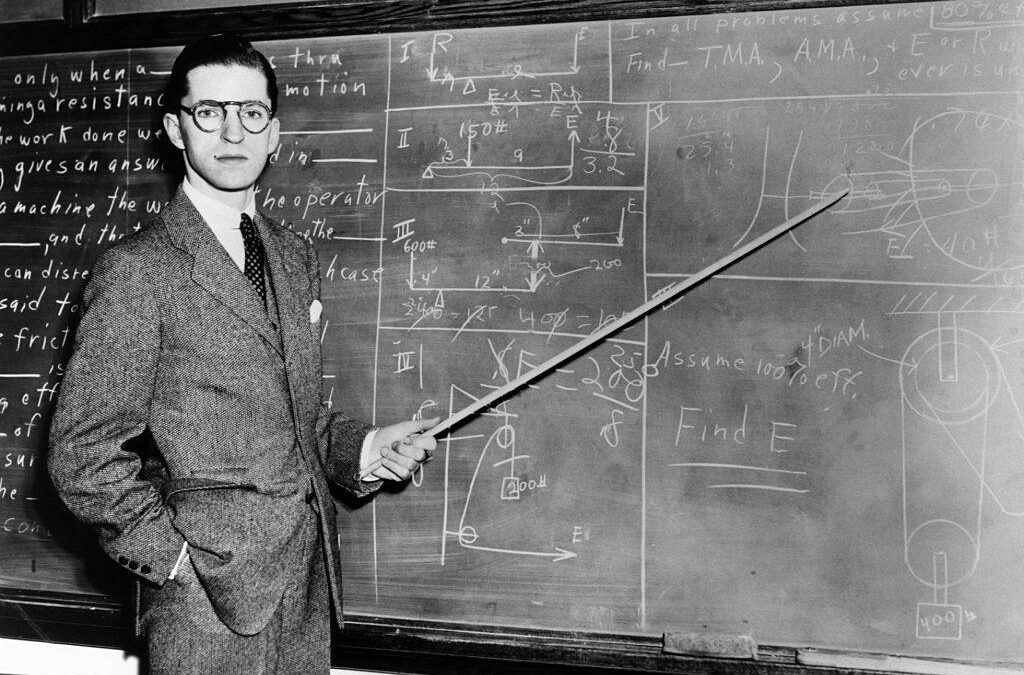 Old photo from approx. 1940s of man teaching at a chalkboard.